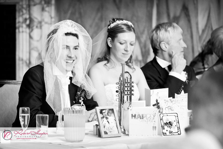 Funny groom wearing bride's veil during wedding speeches 