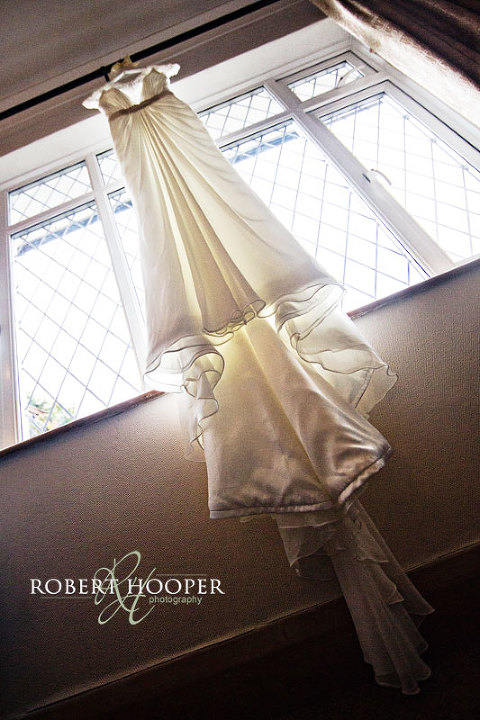 Wedding dress hanging in window with back lighting