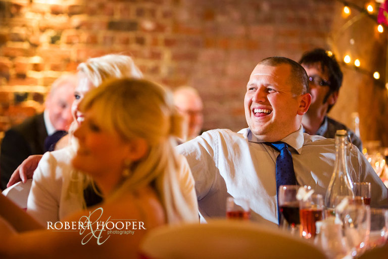 Guests laughing at wedding speeches during Cooling Castle Barn wedding in Rochester, Kent