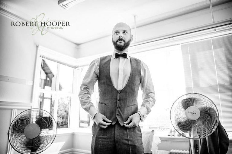 Bridesman adjusting waistcoat during bridal preps at The Manor House in Godalming Surrey
