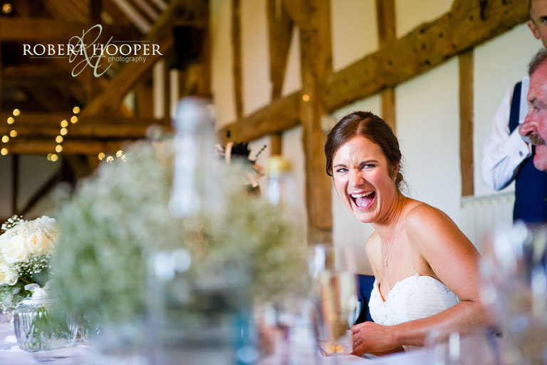 Bride laughing at speeches during wedding breakfast at Surrey wedding venue