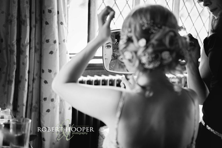 Bride looking in mirror during bridal preps at Cain Manor in Surrey