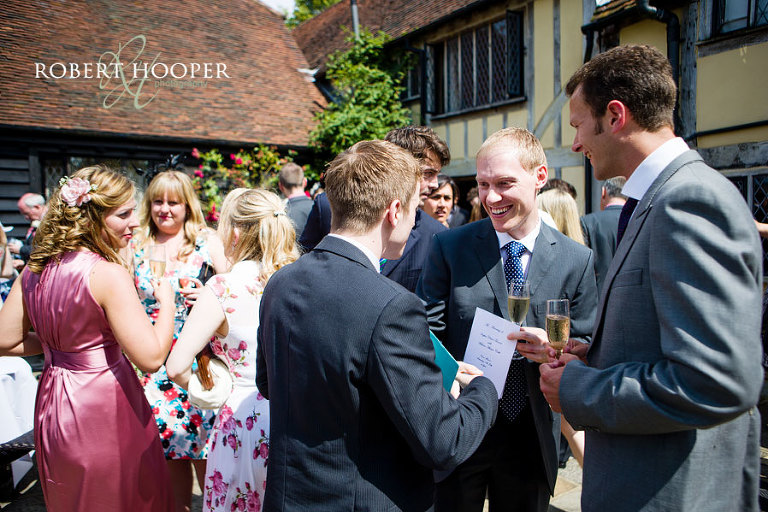 Guests enjoying themselves at champagne and canape reception after wedding at Cain Manor in Surrey