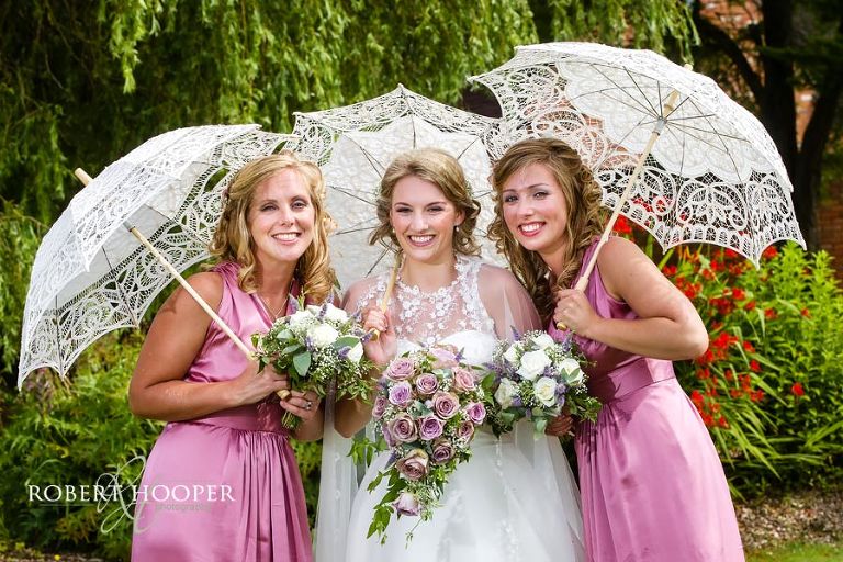 Bridesmaids holding white lacey parasols at Cain Manor wedding venue in Surrey