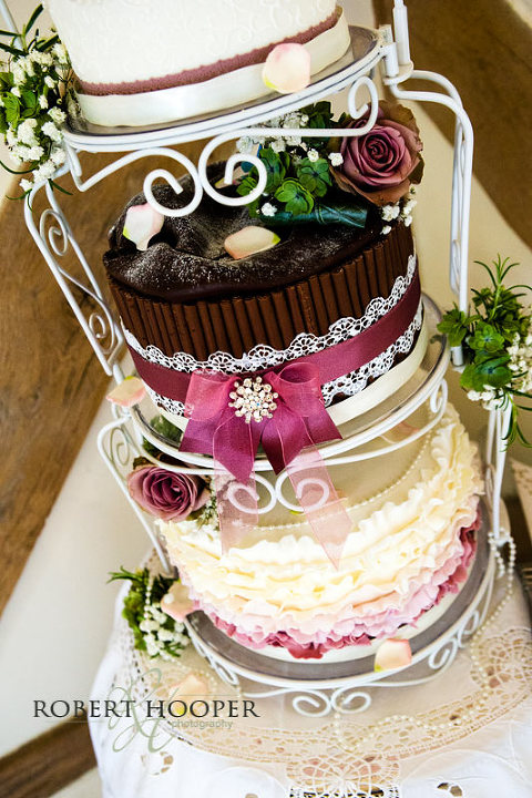 Wedding cake on cake stand decorated with roses at wedding breakfast at Cain Manor Surrey