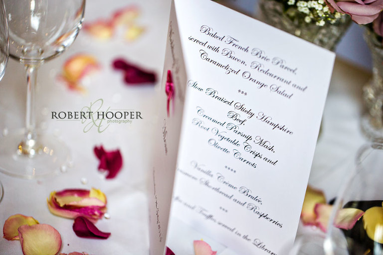 Menu and petals on table at wedding breakfast Cain Manor Surrey