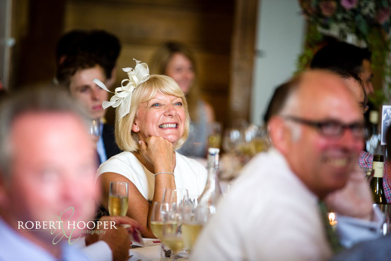 Candid photo of wedding guest laughing during wedding breakfast speech at Cain Manor, Surrey