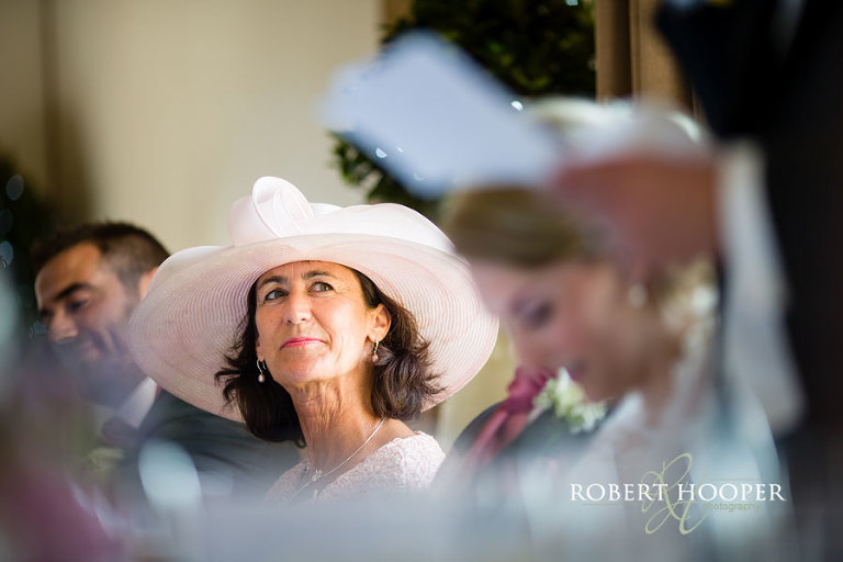 Mother of the groom at wedding breakfast top table wearing a big pink hat with bow at Cain Manor in Surrey