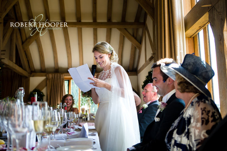 Bride with long veil giving a speech at wedding breakfast, Cain Manor in Surrey