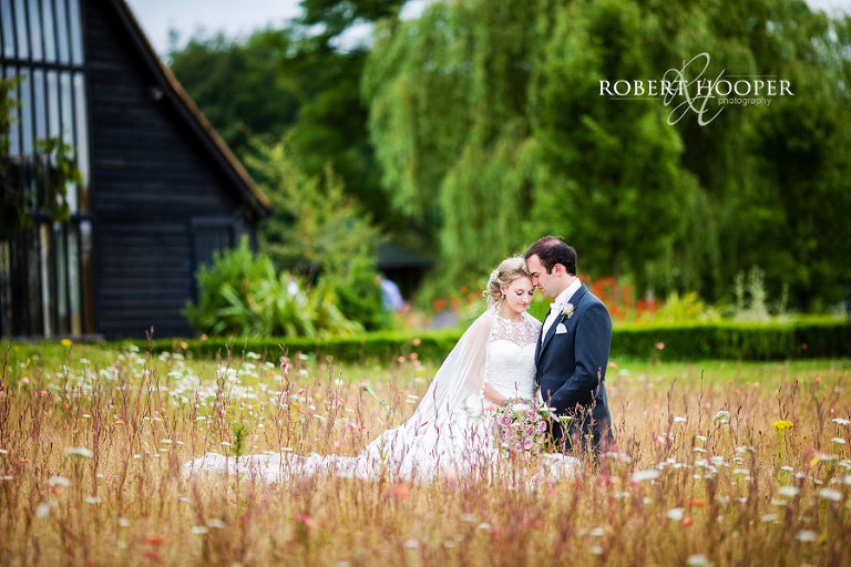 Bride and groom amongst the wild flowers at July wedding at Cain Manor in Surrey