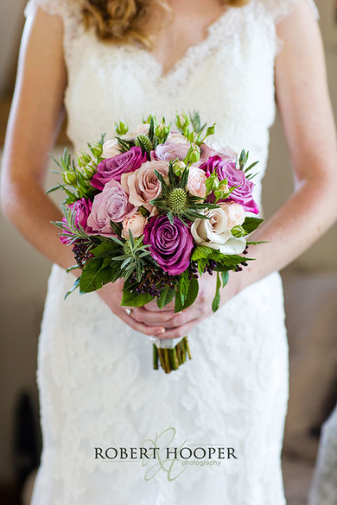 Kent bride holding bouquet of roses before wedding at Cooling Castle Barn in Rochester, Kent