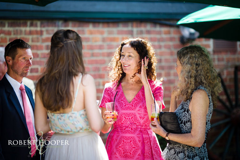 Wedding guests drinking PIMM's and enjoying themselves in the grounds of Cooling Castle Barn, Kent after summer wedding ceremony