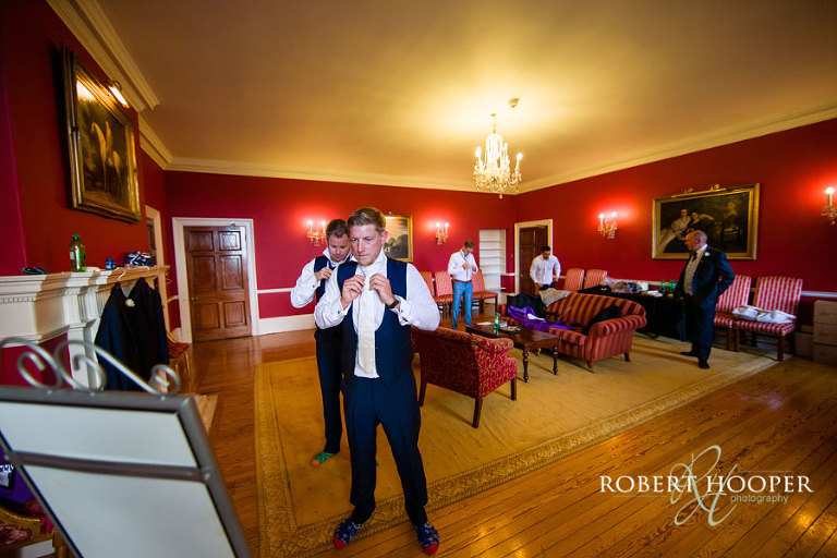 Groom and his groomsmen fixing their tie during preparations for wedding at Addington Palace in Surrey
