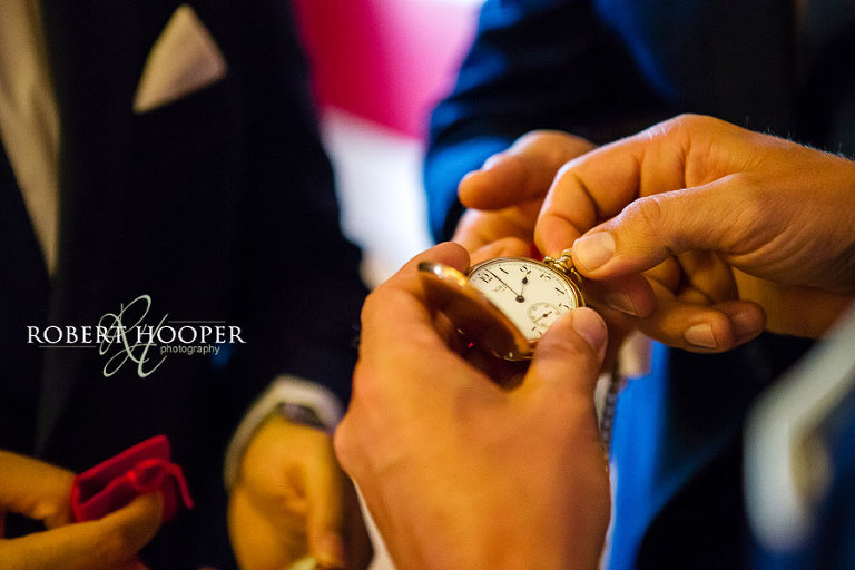 Groom giving his groomsmen present of gold pocket watch before his wedding at Addington Palace, Surrey