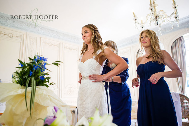 Bride getting in her dress and bridesmaid and mum helping do her up before her wedding