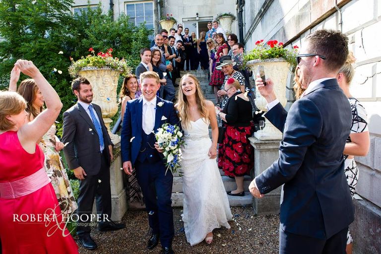 Wedding guests throwing confetti at bride and bride groom after their marriage at Addington Palace in Croydon, Surrey
