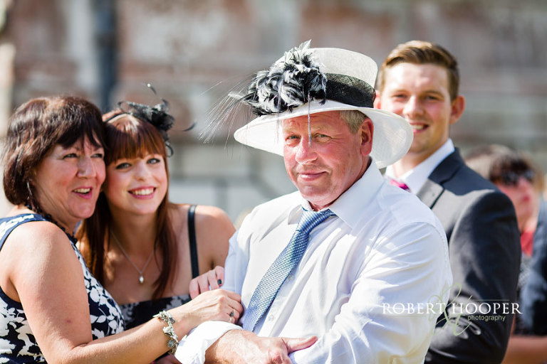 Male wedding guest wearing lady's hat at July wedding at Addington Palace in Croydon, Surrey