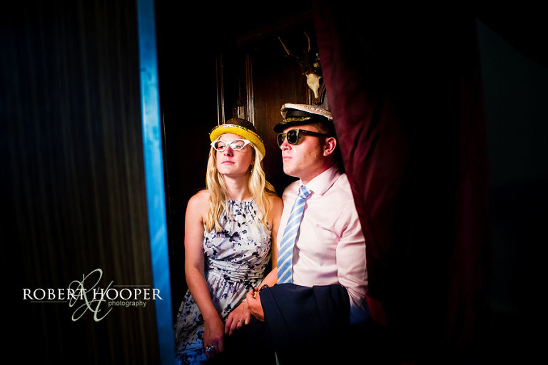 Couple wearing specs and hats posing in a photo booth at wedding in Addington Palace, Croydon in Surrey