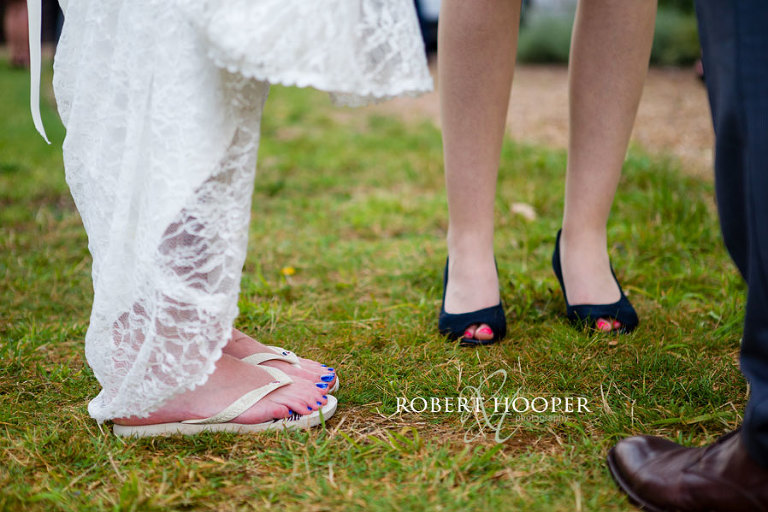 Bride in flip flops with blue nail varnish matching her bridesmaids' dresses and her flowers at wedding drinks reception at Addington Palace, Croydon Surrey