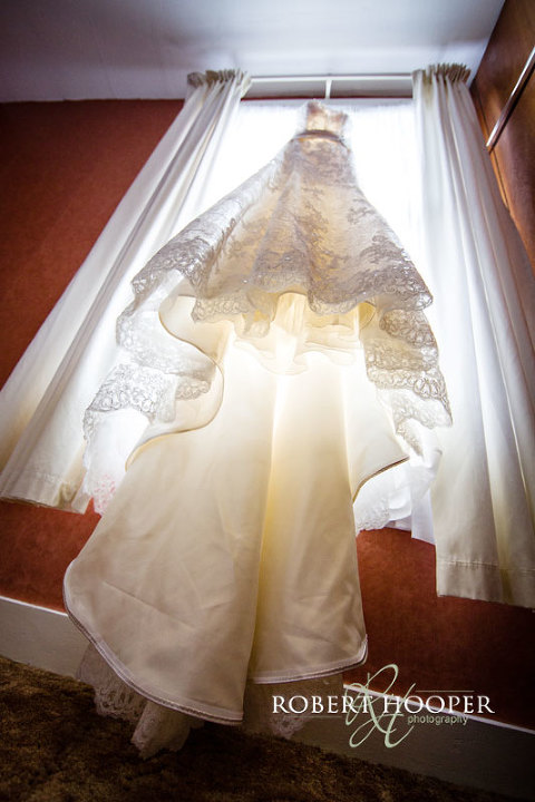 White wedding dress hanging up before bride gets ready for church wedding at St Andrew the Apostle Parish Church then Addington Palace