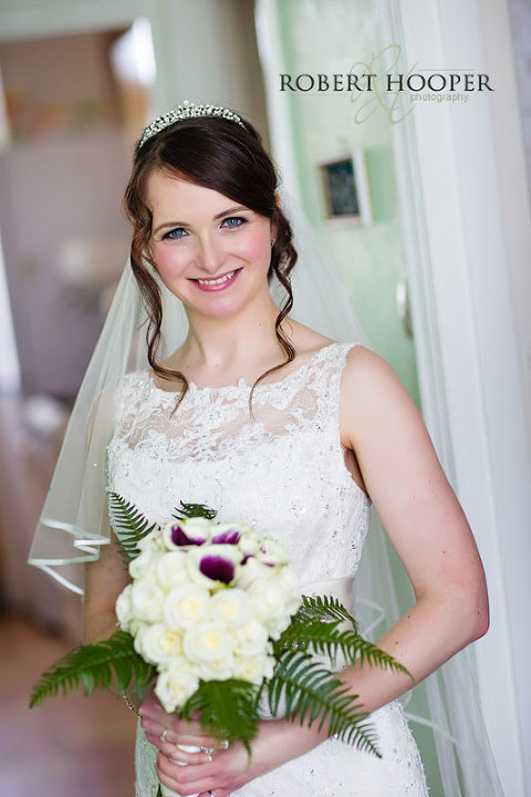 Bride wearing tiara and holding purple and white bouquet before her wedding at St Andrew the Apostle Church and Addington Palace Surrey