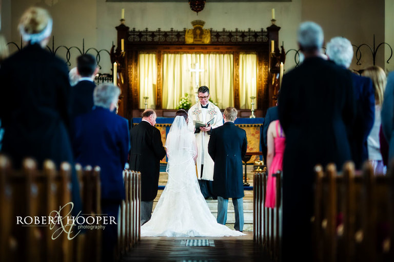 Bride and groom saying their vows during their wedding ceremony at the alter in St Andrew the Apostle Parish Church in Catford, London