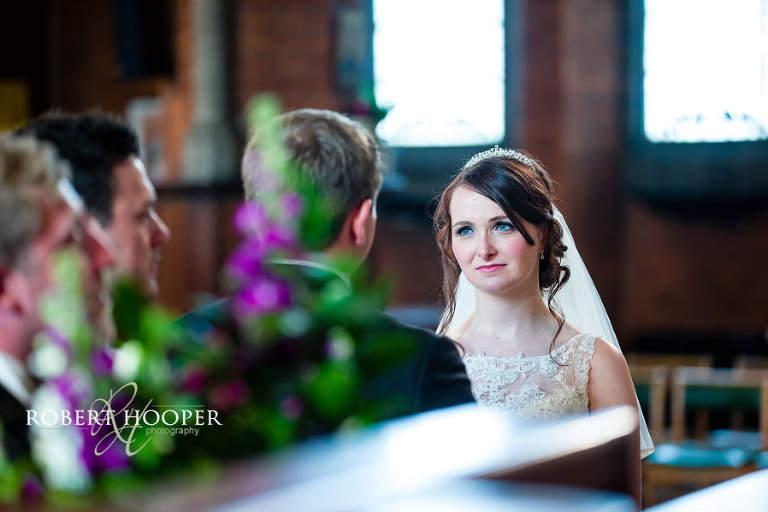 Tender look from bride to groom during wedding ceremony at St Andrew the Apostle Church in Catford London