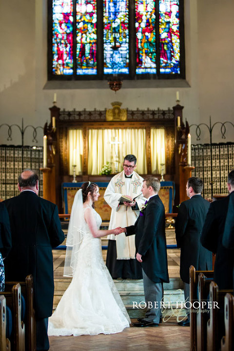 Bride and groom exchanging wedding rings during vows on wedding day at St Andrew the Apostle Church in Catford, London