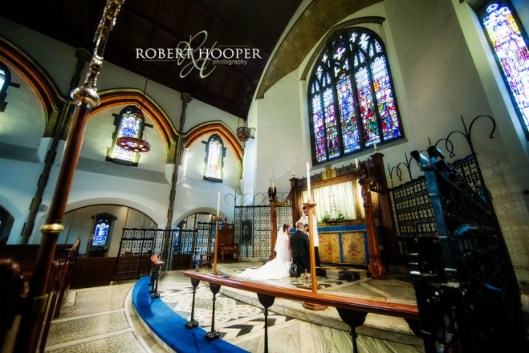 Bride and groom kneeling at the alter for blessing during their wedding ceremony at St Andrew the Apostle Church in Catford, London