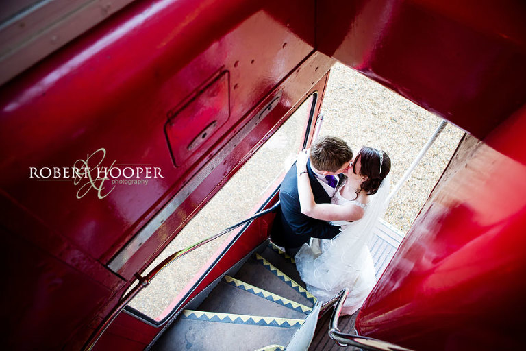 Bride and groom in an embrace on red London bus on their wedding day in Surrey