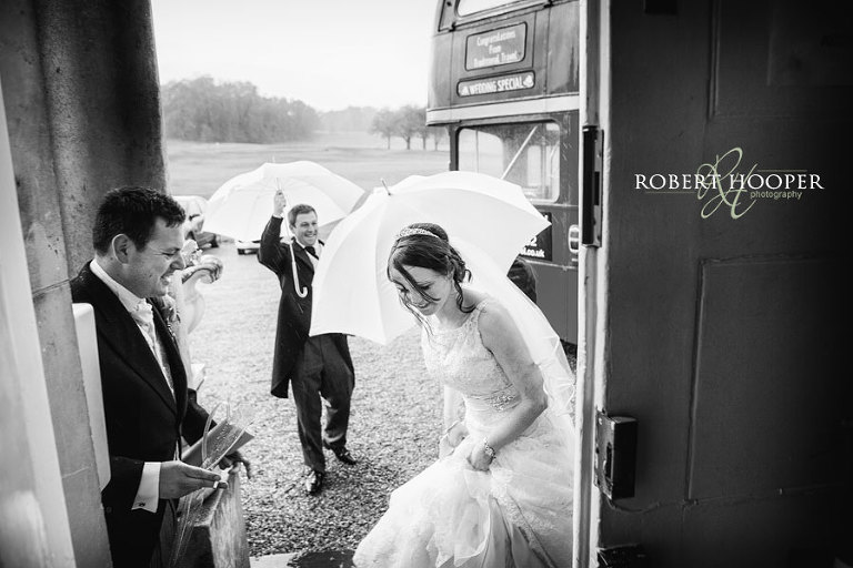Bride entering Addington Palace on rainy wedding day