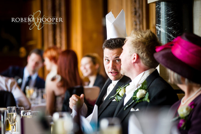 Best man with napkin on his head during wedding breakfast in the Great Hall at Addington Palace Surrey