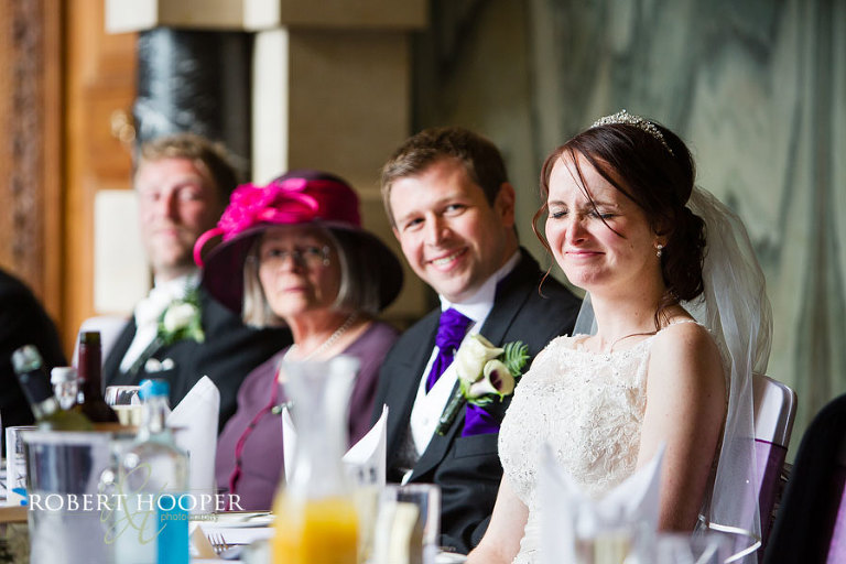 Bride laughing at dad's speech during wedding breakfast in the Great Hall at Addington Palalce, Surrey