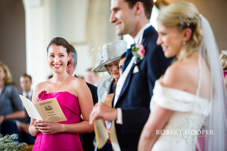 Natural shot of Bridesmaid smiling at wedding couple during marriage service at All Saints Church, Orpington, Kent
