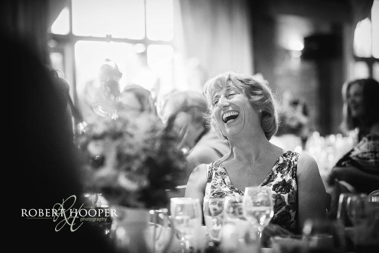 Black and white photography of guest laughing during speeches at Kent wedding venue