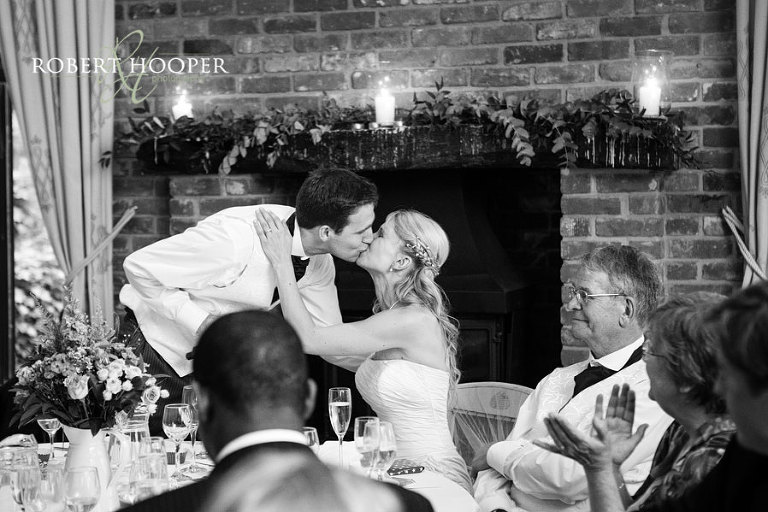 Kent bride and her bride groom kissing after groom's speech at Westerham Golf club wedding venue in Kent