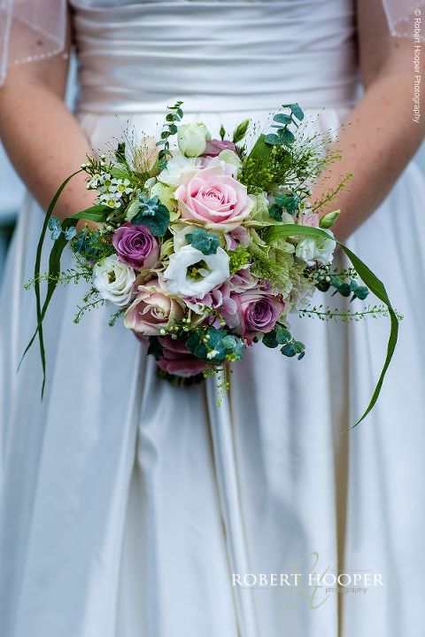 Bride holding her bouquet of pink roses on her wedding day at Bix Manor, Henley-on-Thames in Oxfordshire