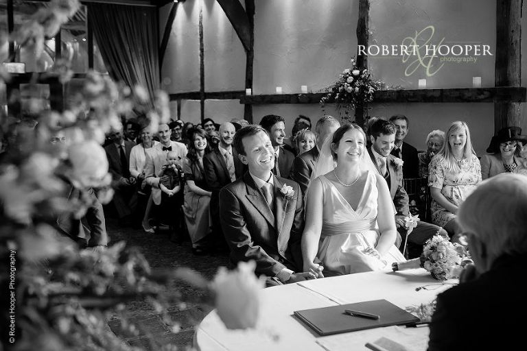 Bride and groom share a laugh with registrar during their civil wedding ceremony at Bix Manor, Henley-on-Thames, Oxfordshire