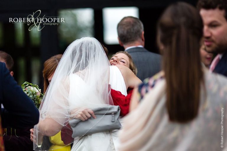 Wedding guest giving bride a big hug after her ceremony at Bix Manor, Henley-on-Thames, Oxfordshire