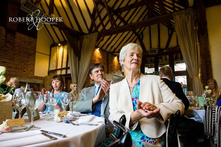 Guests clapping during speeches at wedding breakfast in the Great Tithe Barn at Bix Manor, Henley-on-Thames, Oxfordshire