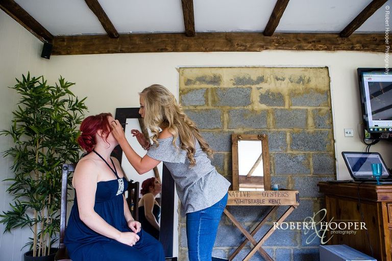 Bridesmaid having make-up applied during bridal preps for wedding in Send, Surrey