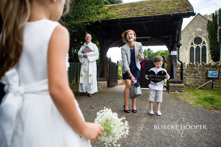 Page boy holding sign for bride's arrival at church in Send, Surrey