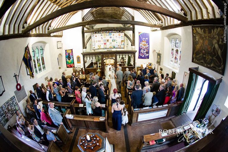 Shot of whole congregation and bride walking down the isle on her wedding day in Send, Surrey