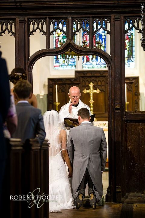 Bride and bride groom kneeling at the alter for blessing from vicar during their wedding ceremony at Send Church in Surrey