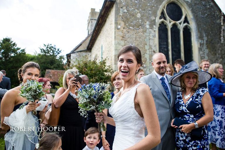 Bride laughing after confetti throwing on wedding day at Send Church in Surrey
