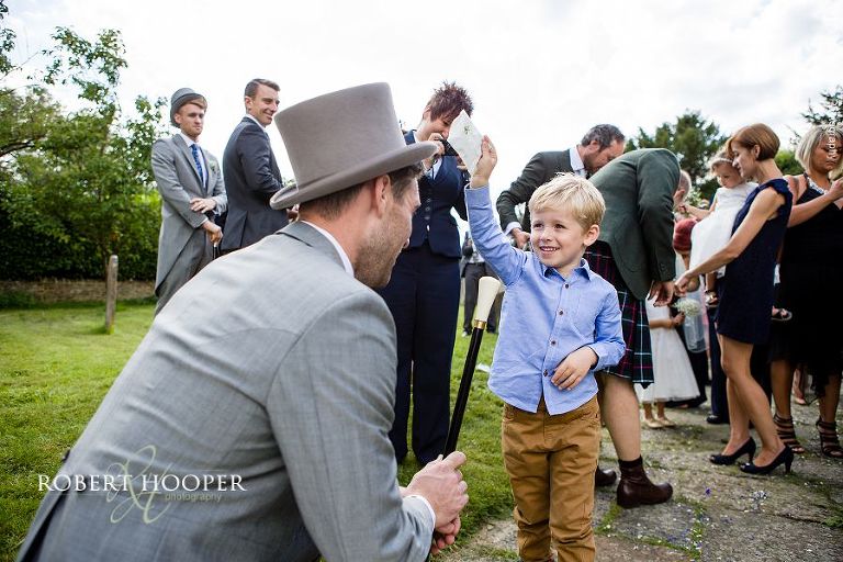Young boy trying to thrown confetti over groom on his wedding day at Send Church in Surrey