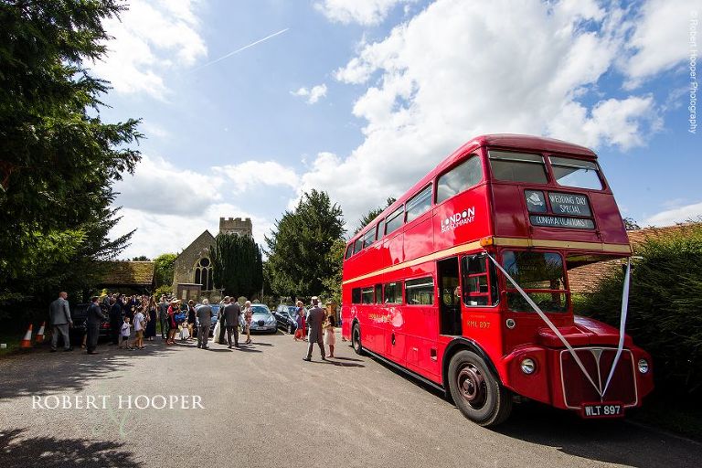 Red London bus waiting outside Send Church to take guests to reception in Surrey
