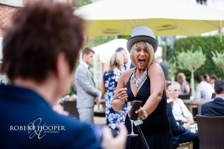 Wedding guest dancing wearing groom's hat and holding cane at wedding reception Stag on the River, Eashing in Surrey