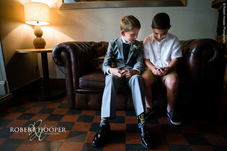 Young boys playing with mobile phone at wedding reception at Stag on the River, Eashing in Surrey