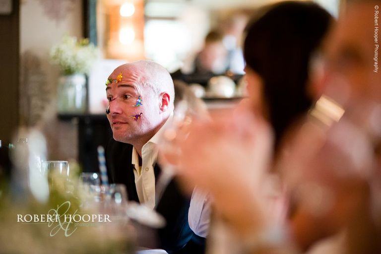 Wedding guest with dinosaur stickers on his face (entertaining the children) at wedding reception at The Stag on the River, Eashing in Surrey